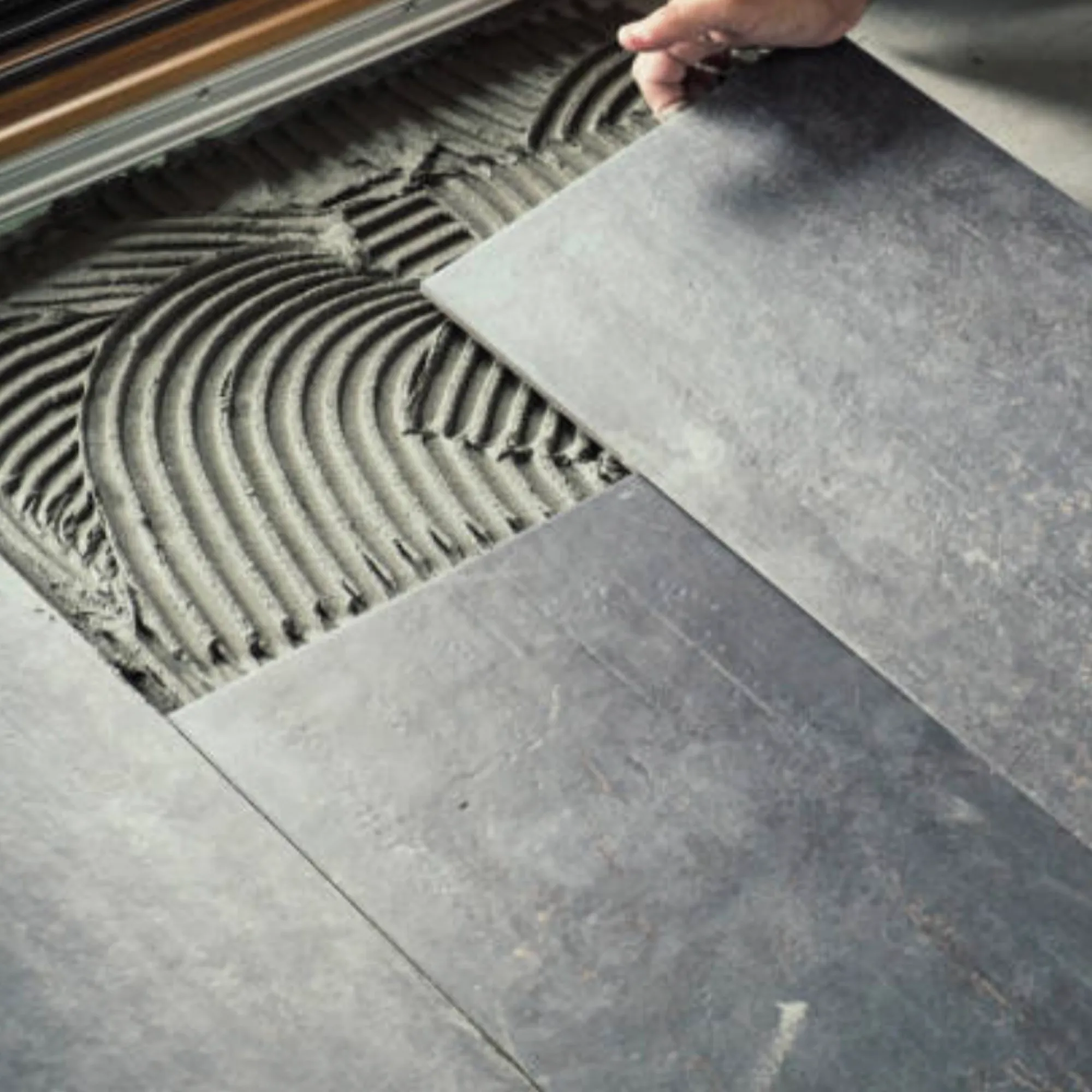 Pose de carreaux grand format sur un lit de colle au sol