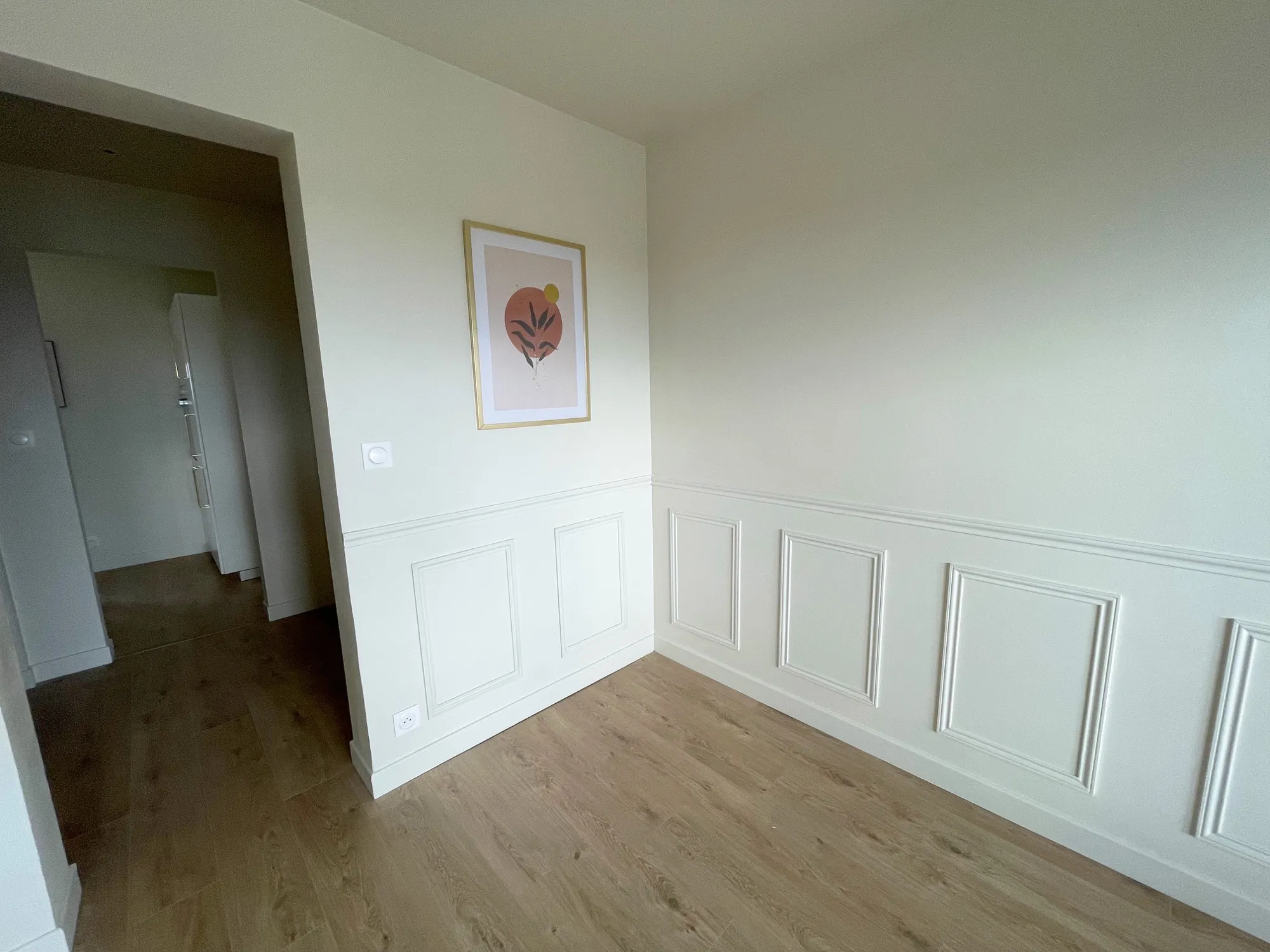 Pièce repeinte en blanc avec soubassement à moulures et parquet clair