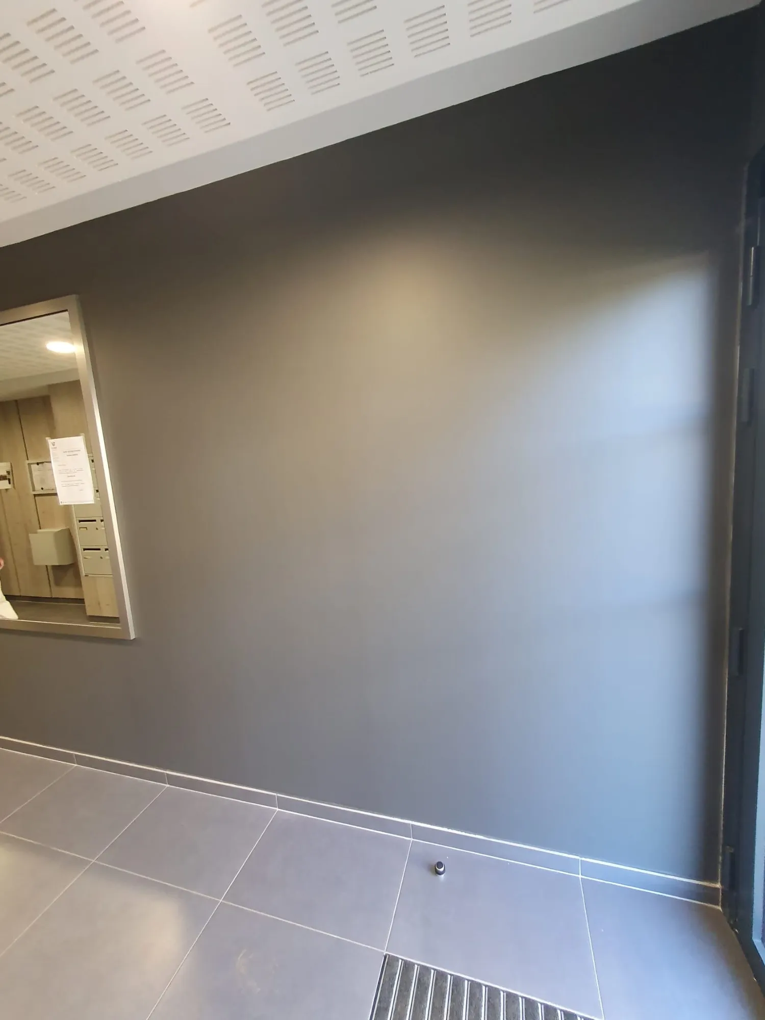 Mur repeint en gris anthracite dans un hall carrelé