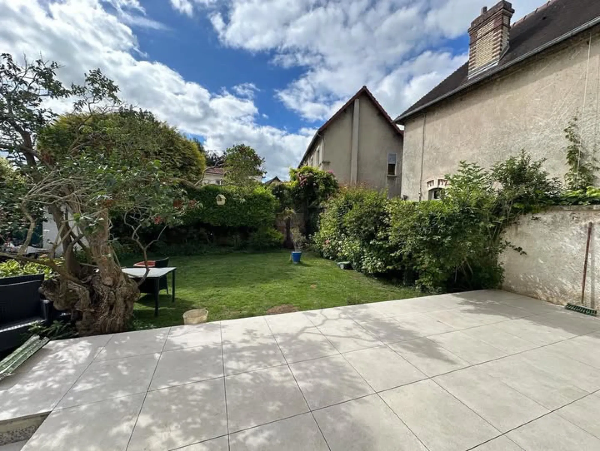 Terrasse en grandes dalles claires ouvrant sur un jardin